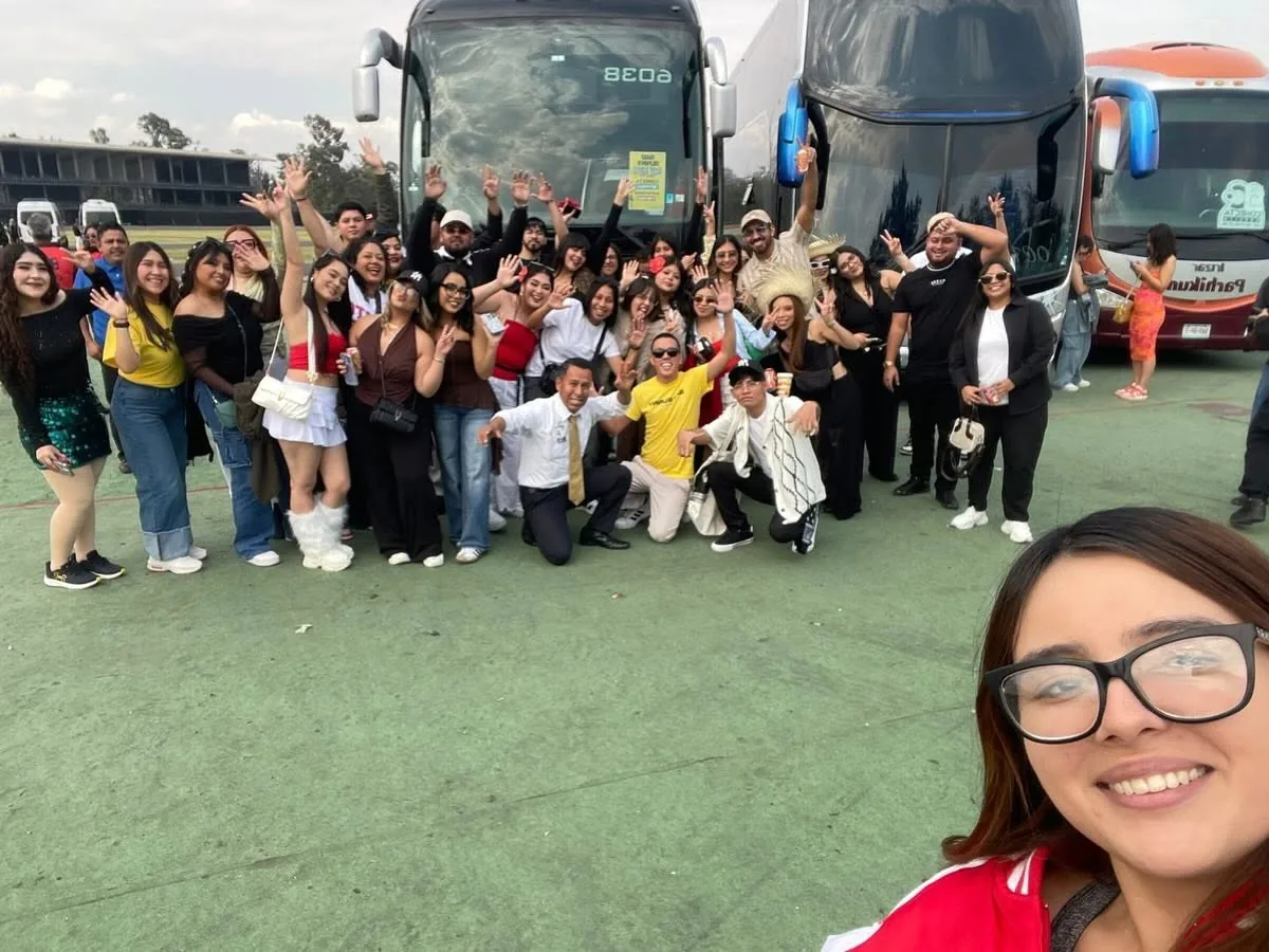 Grupo del tour festejando con los brazos arriba frente a los camiones