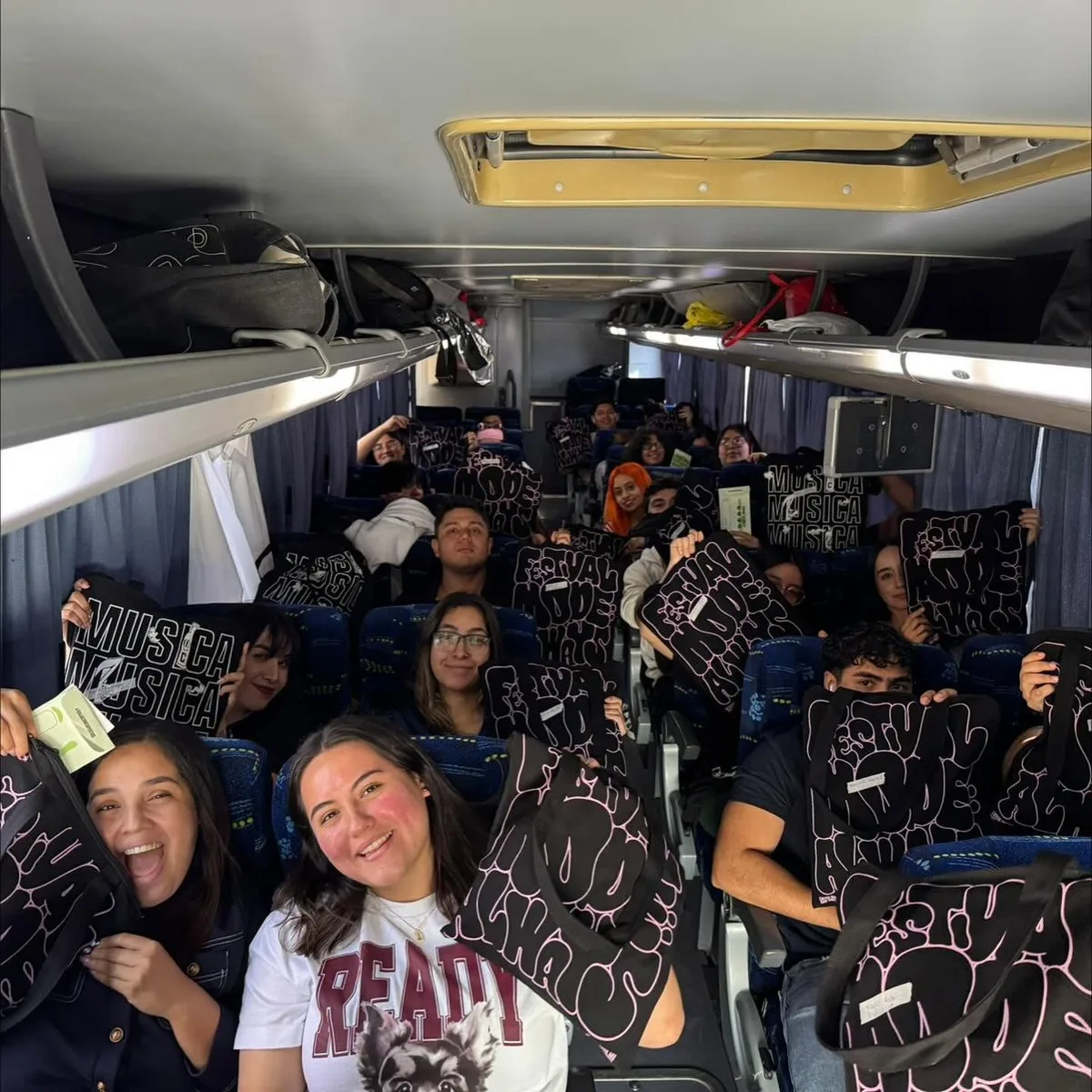 Viajeros del tour levantando sus tote bags del Kit Conecta dentro del camión